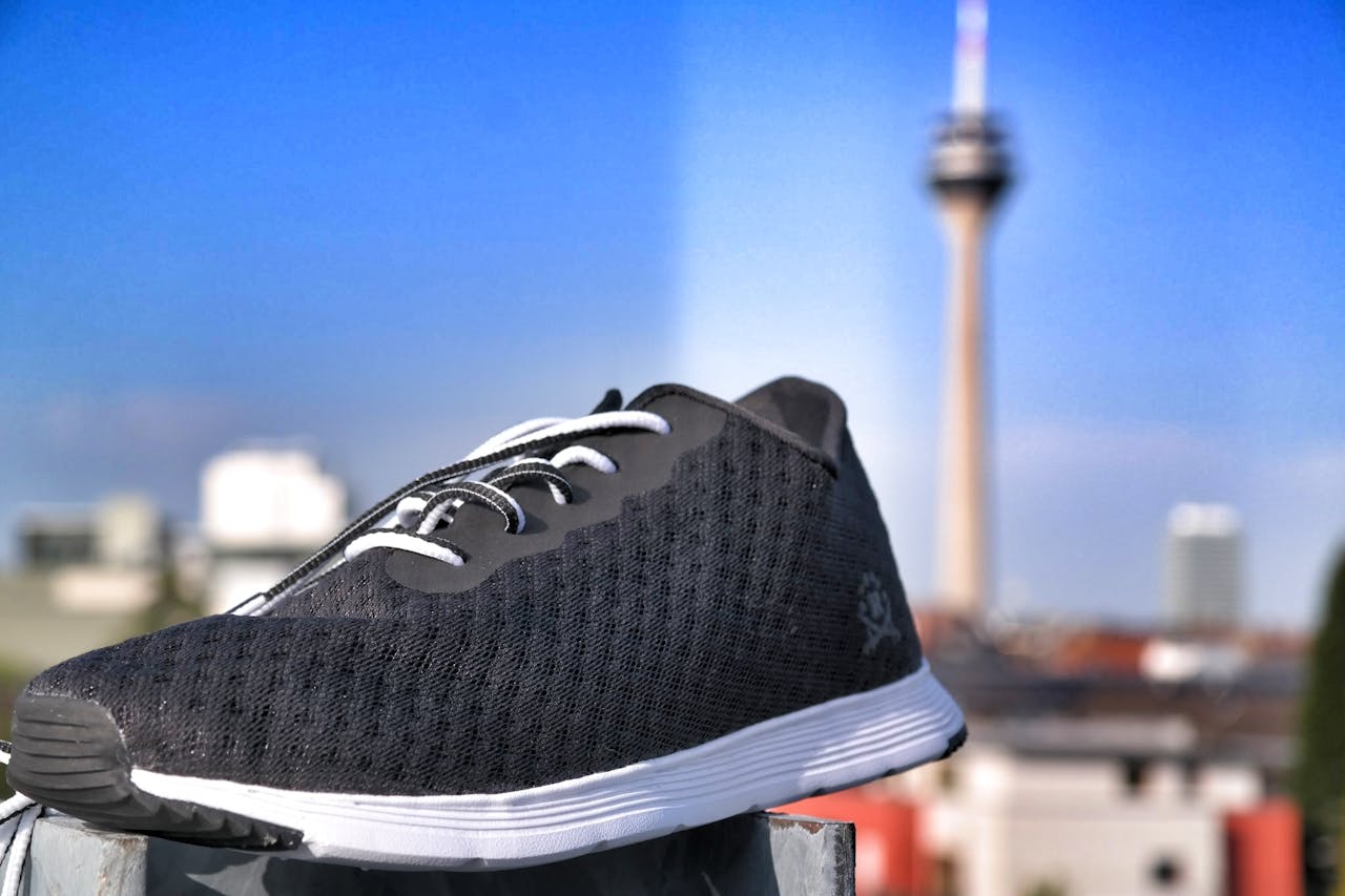 services-04 Modern black sneaker prominently displayed against a vibrant city skyline backdrop.